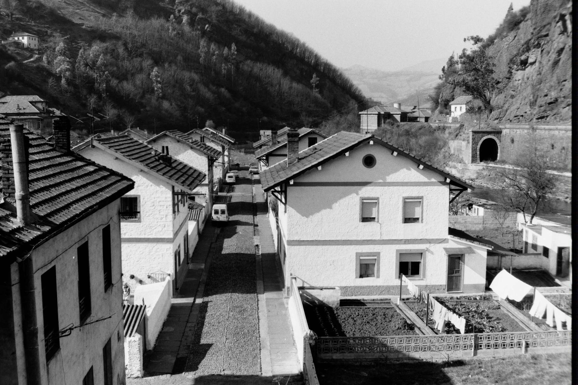Vista general de las viviendas, huertas y vía del ferrocarril en el poblado de Bustiello
