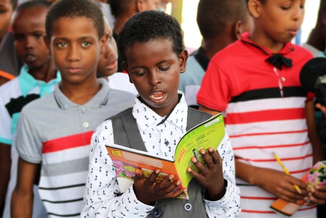 Leyendo Niño leyendo en una fila de niños