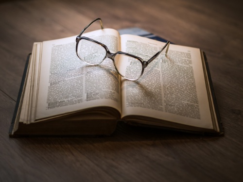 Fotografía en color de un libro abierto con unas gafas encima
