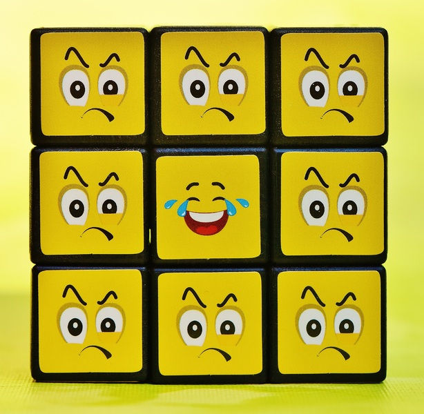 Una cara de un cubo de rubik formada por emoticonos en ves de por colores. Ocho emoticonos enfadados rodean a uno feliz.