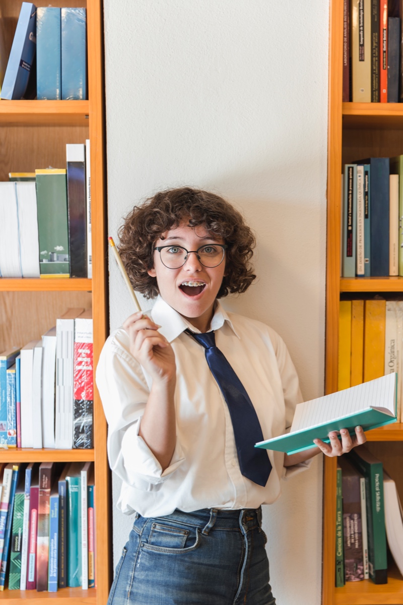 Chica adolescente emocionada tener idea en la biblioteca Chica adolescente emocionada al tener una idea en la biblioteca