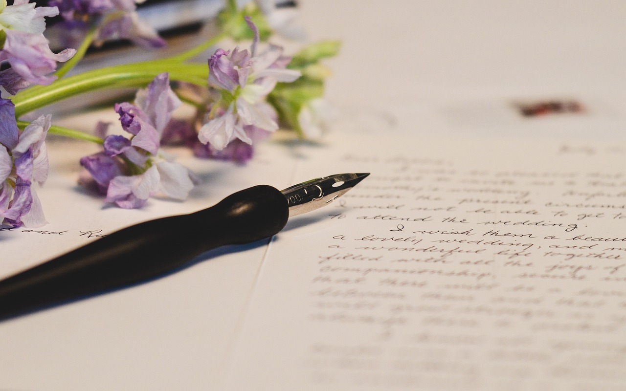 Bolígrafo, Escritura a mano y Escribiendo Fotografía a color con una carta manuscrita a mano en primer plano. Sobre ella hay una pluma estilográfica. A la derecha, un ramillete de flores violetas.