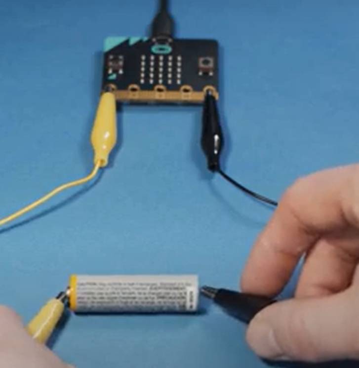 Tarjeta microbit conectada por cables a una pila AA