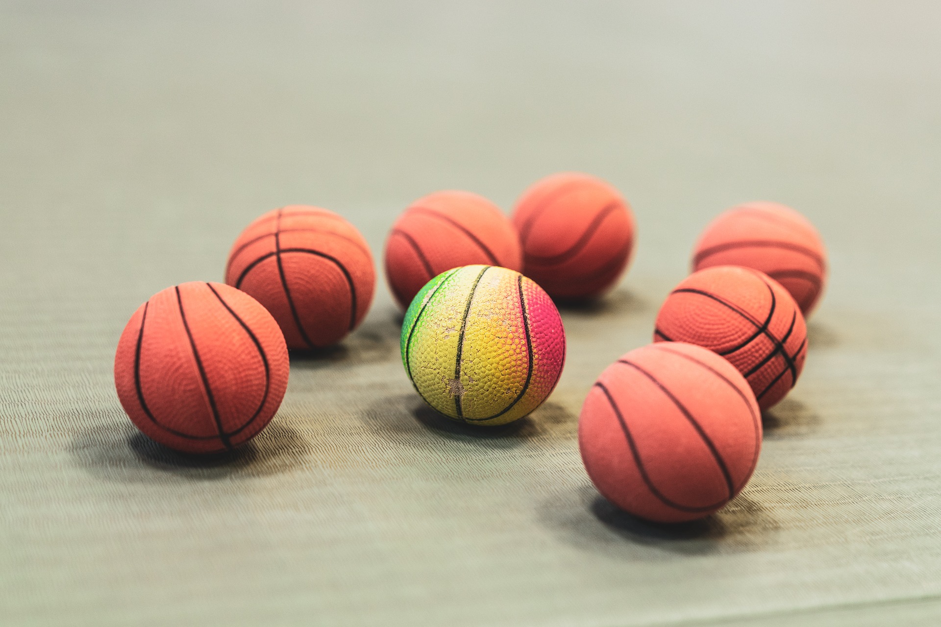 7 balones de baloncesto naranjas y uno en el centro multicolor