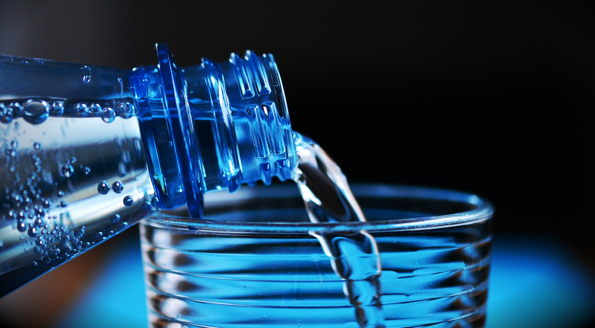 Agua cayendo de una botella a un vaso